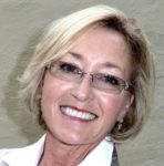 A woman with glasses smiling for the camera.