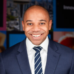 A man in a suit and tie smiling for the camera.