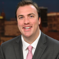 A man in a suit and tie smiling for the camera.