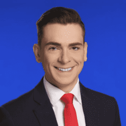 Man in suit with a red tie smiling.